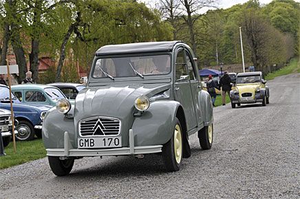 Halvtidig Citroën 2CV med bakhängda framdörrar följd av en lite nyare Charleston i ovanlig färgkombination.