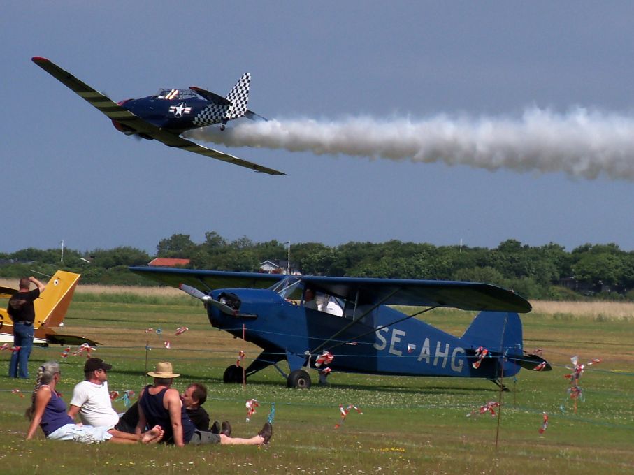 "Check er tail" vrålar förbi. Det är en North American harvard med förfluteti svenska flygvapnet där denna typ hette Sk16. Under den står ett mindre känt svensk plan, en GV38. Detta var en licensbyggd Rearwin Sportster som byggdes i 14 exemplar hos Götaverken 1938-41.
