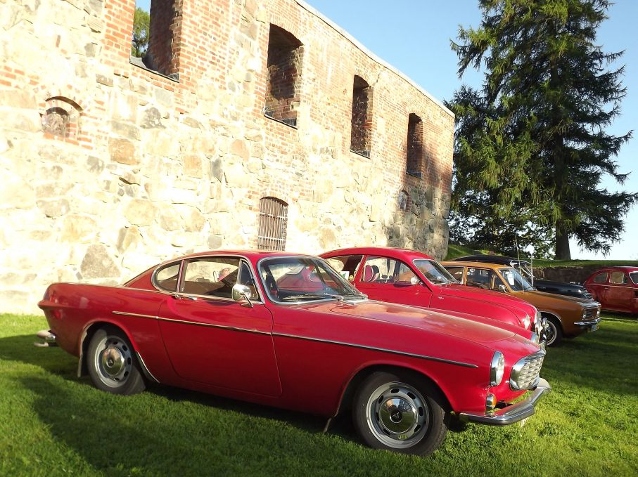 Volvo 1800S, Saab 93 och Morris marina framför ruinen