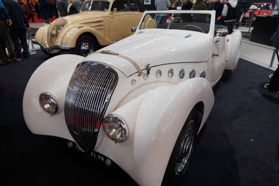 En Darl’mat, den extravaganta varianten av den mer sedesamma Peugeot 402 som ses i bakgrunden. Det är sent 1930-tal och Peugeotåterförsäljaren Emile Darl’mat vill sätta sitt namn på en bil och ställa upp i LeMans. Peugeot backar honom och ännu en fransk bilikon skapas.